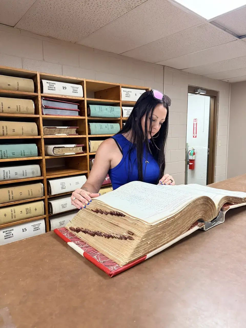 Crystal reviewing a historic Grady County property ledger during archival research