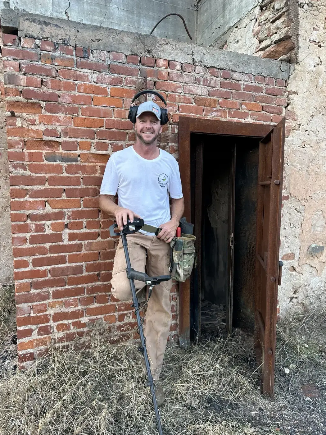 Derik Keith with metal-detecting equipment at a historic brick structure