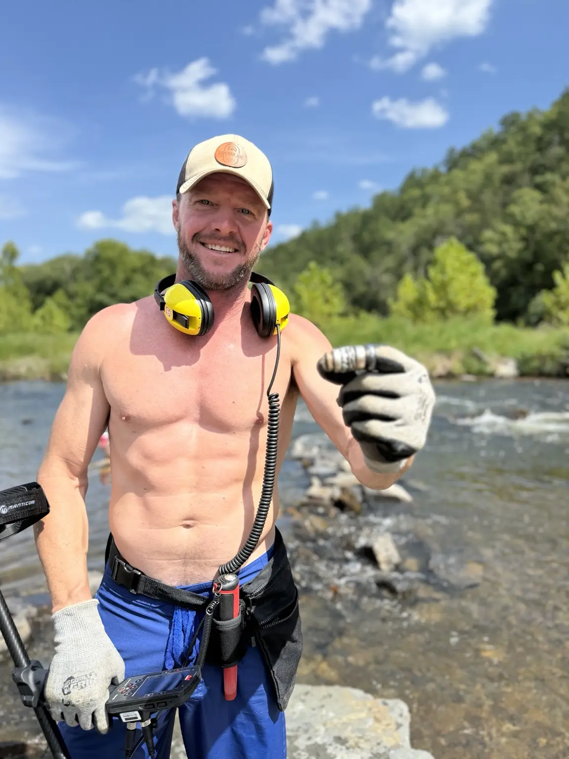 Derik Keith displaying recovered rings beside an Oklahoma river